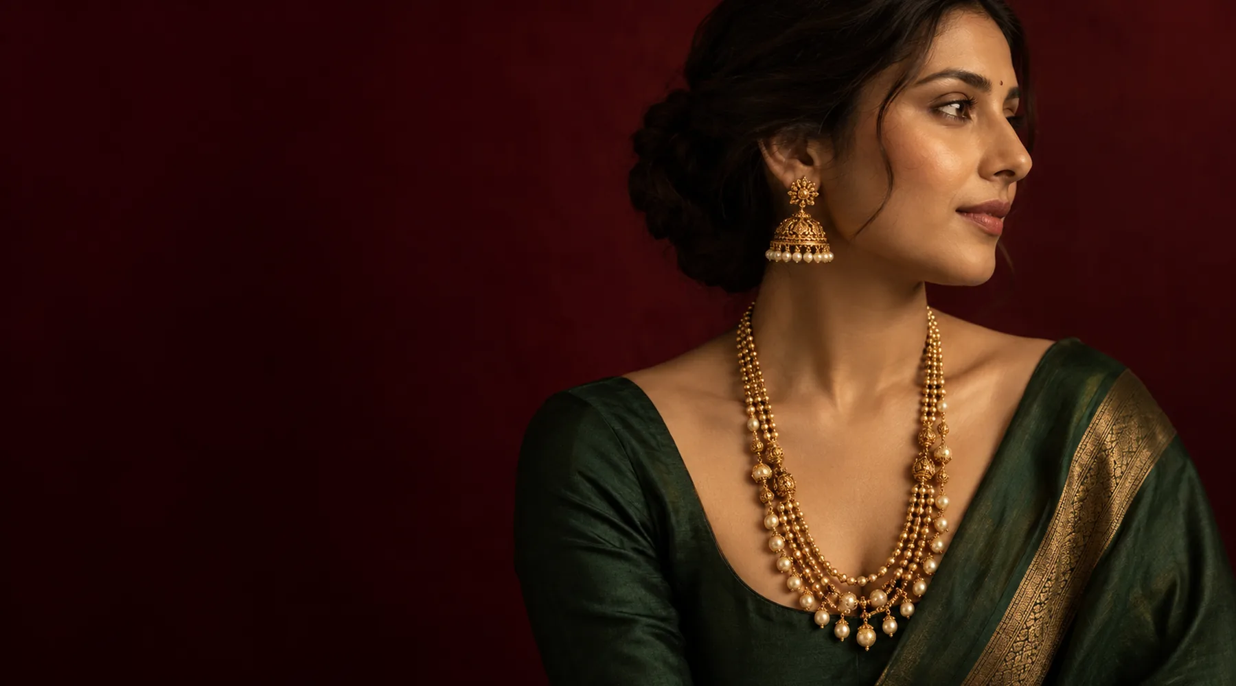 A woman wearing a long layered gold chain necklace with pearls
